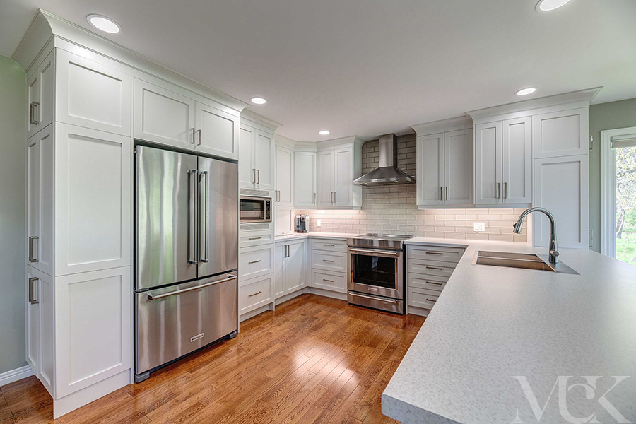 Clean and modern style kitchen renovation with white cabinets and cupboards, stainless steel appliances and white counter tops.